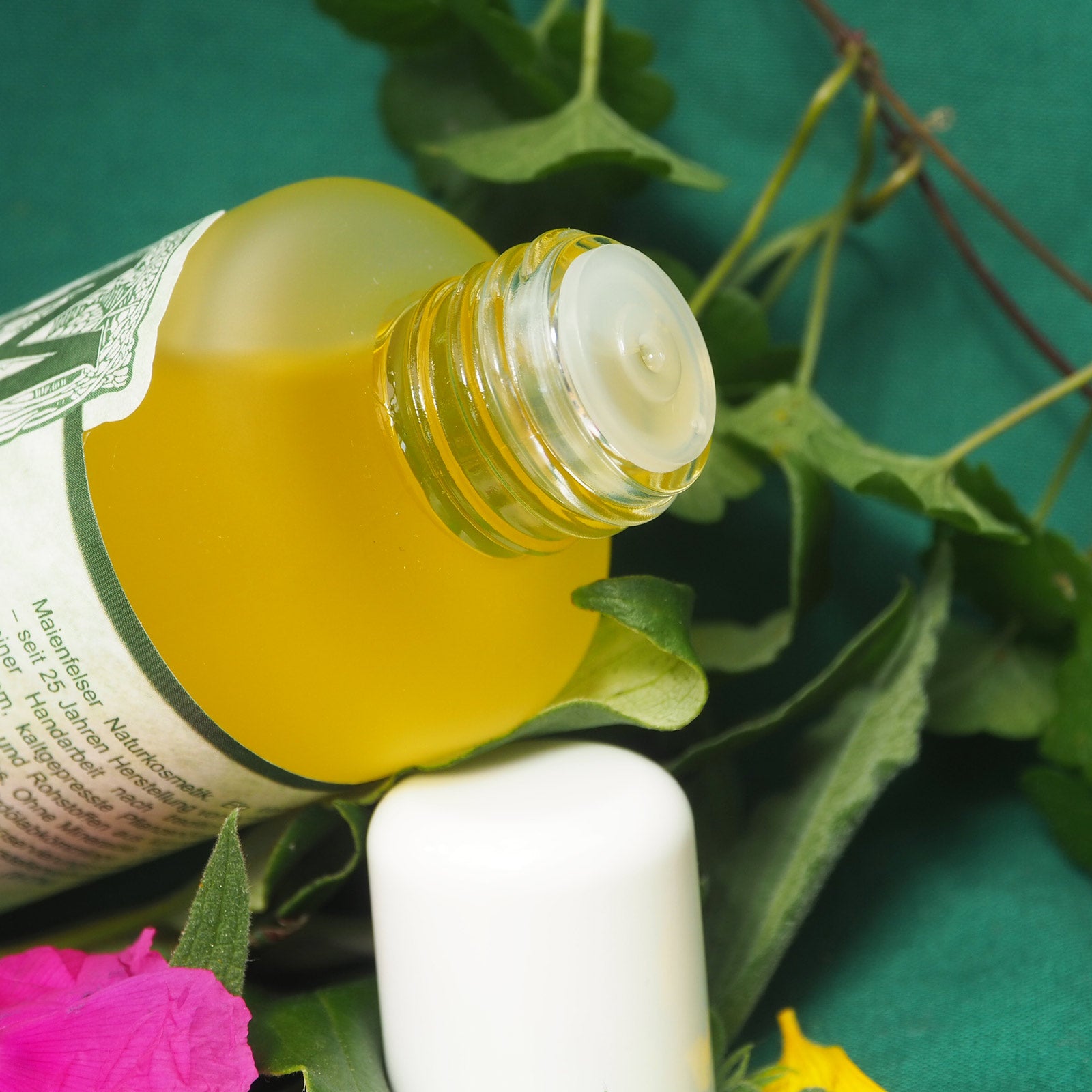 Glasflasche mit TRopfeinsatz geöffnet. Der HIntergrund ist geschmückt mit einer Blätterranke